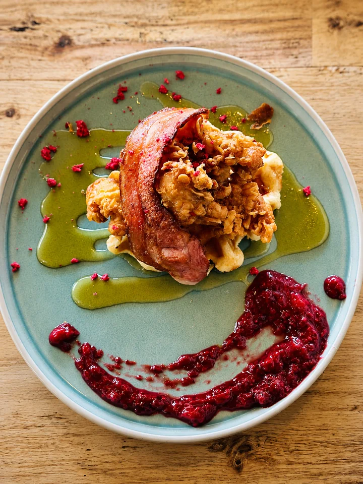 Breakfast dish with bacon, fried chicken and berry sauce
