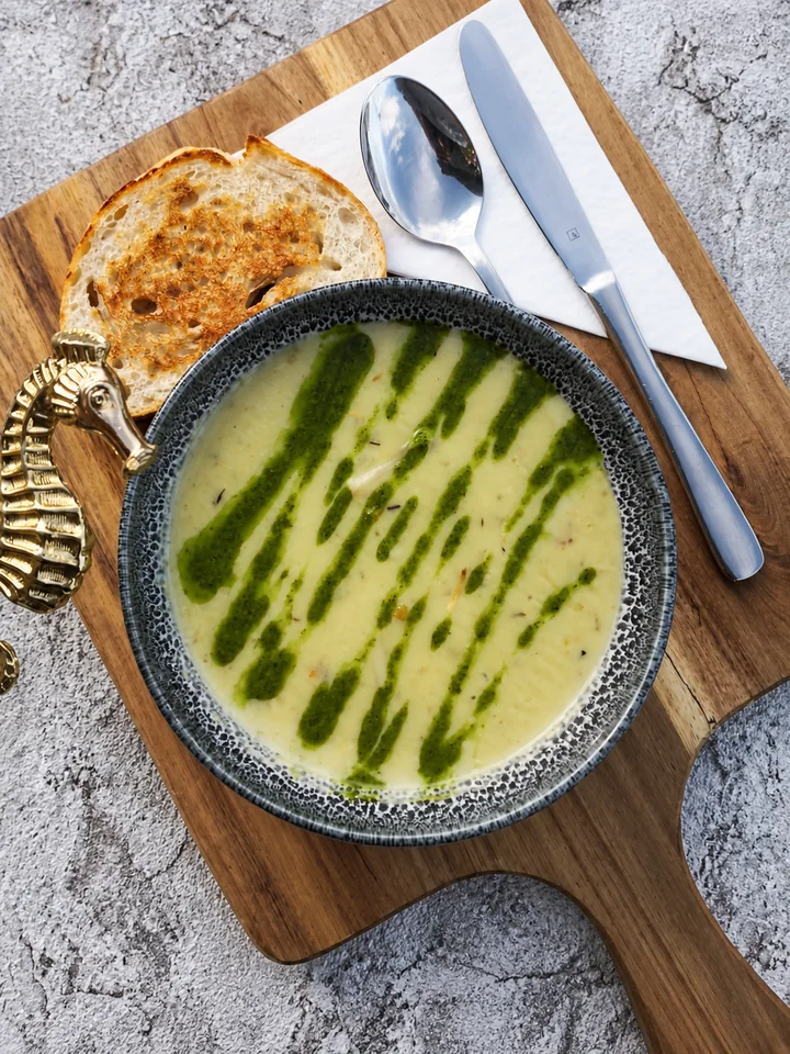 Creamy soup with toast and spoon on a wooden board